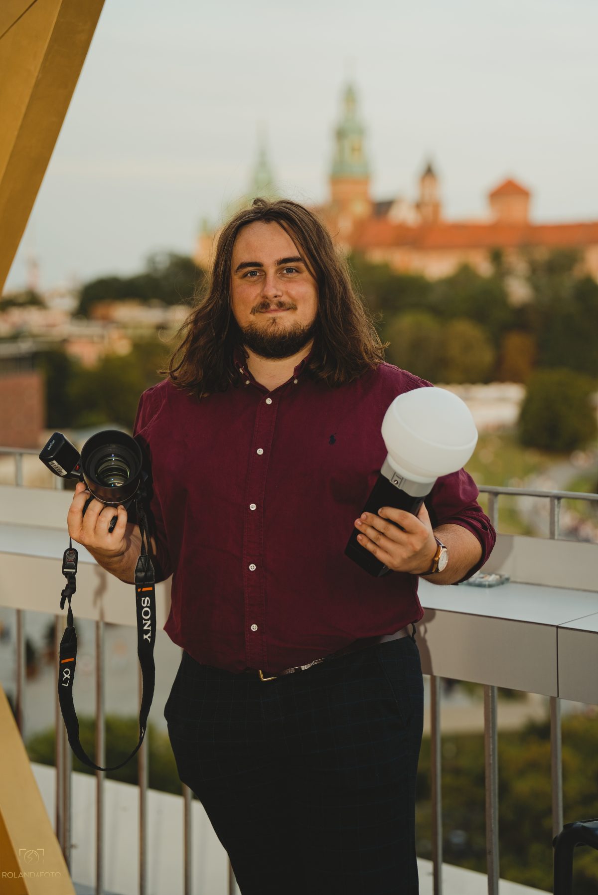 Fotograf Roland Mika z aparatem i lampą na tle Wawelu