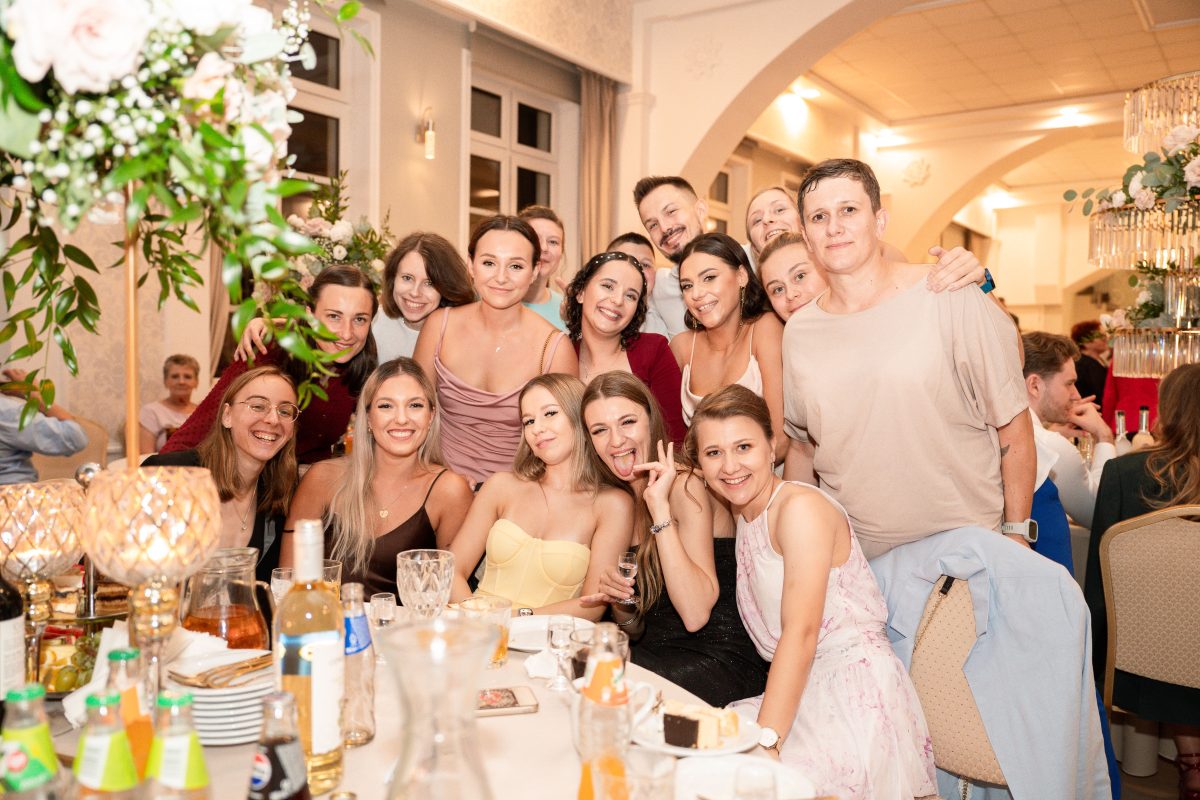 Goście pozują do wspólnego zdjęcia przy weselnym stole