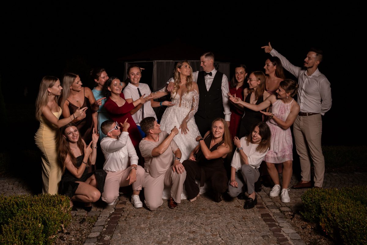 Para młoda z grupą gości na nocnym zdjęciu grupowym