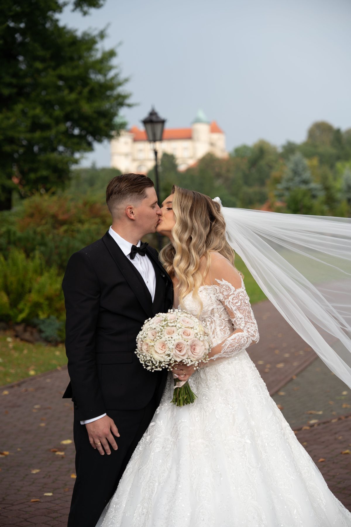 Pocałunek pary młodej z zamkiem w Nowym Wiśniczu w tle