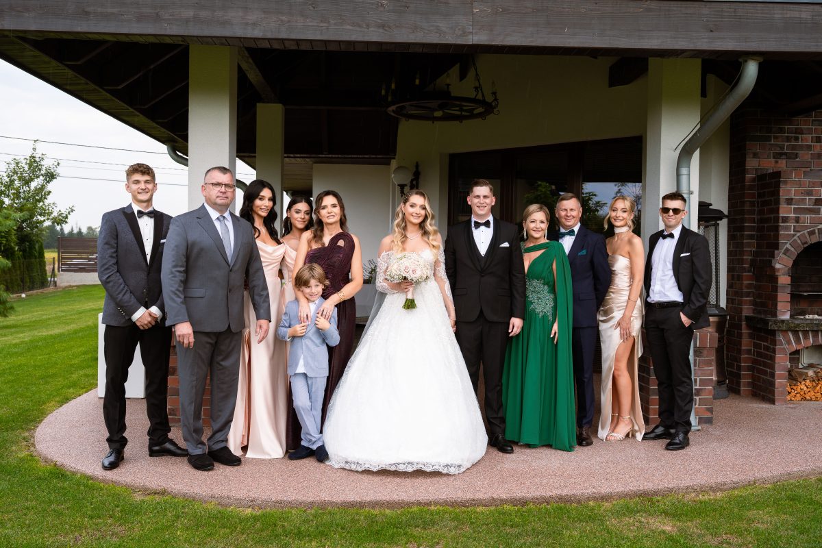 Zdjęcie grupowe pary młodej z najbliższą rodziną przed domem
