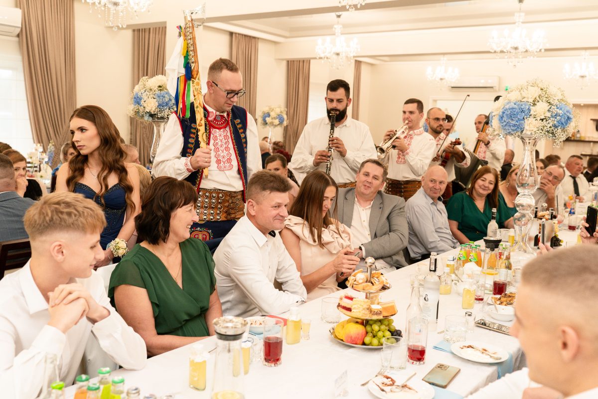 Muzycy w strojach góralskich grają dla gości przy weselnym stole