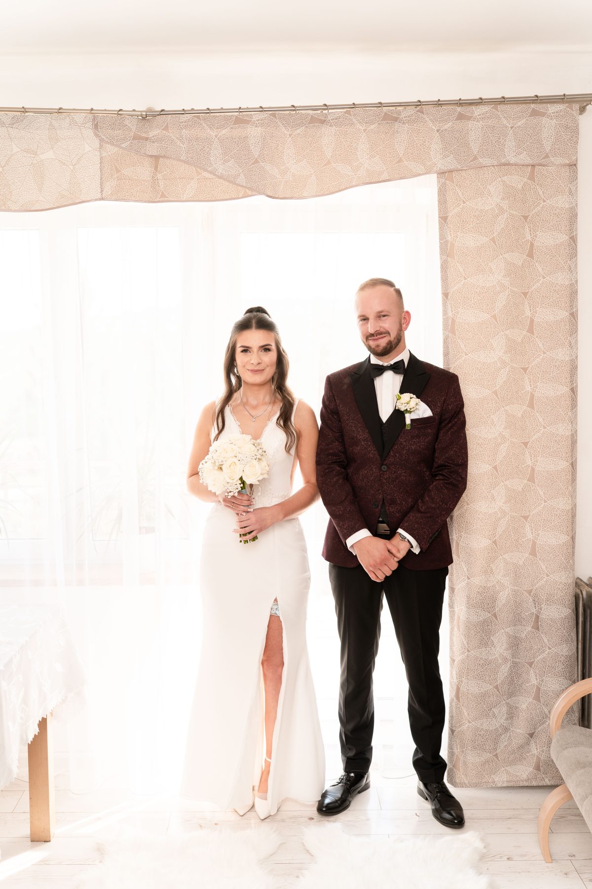 Portret pary młodej w świetle okna, pan młody w bordowej marynarce