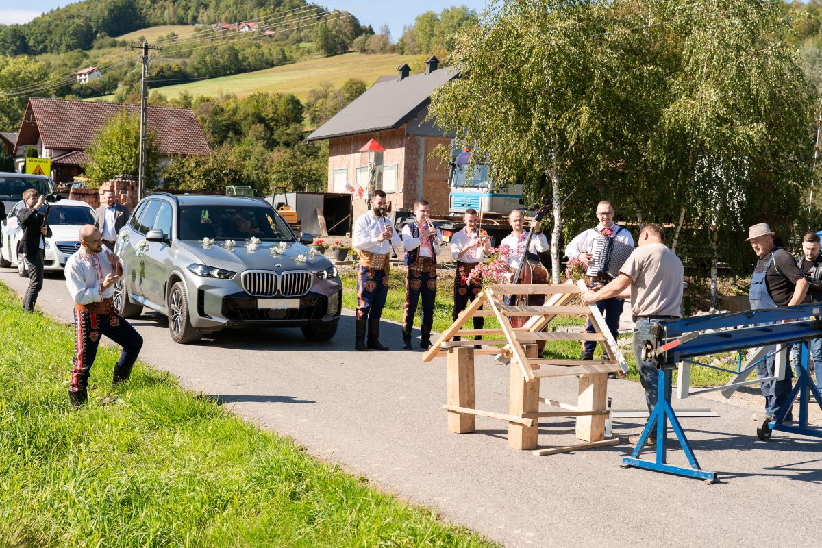 Brama weselna na wiejskiej drodze, kapela zatrzymuje samochód pary