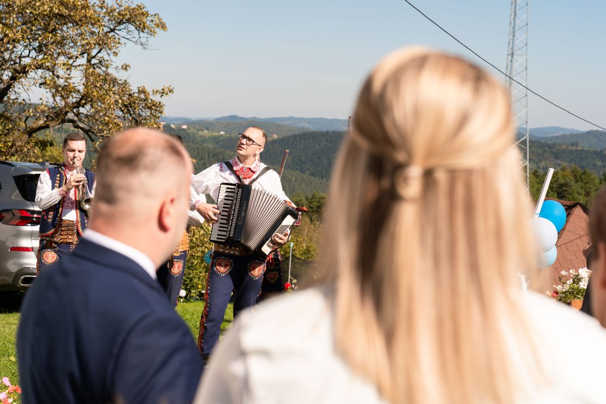 Kapela góralska gra przy bramie weselnej, goście patrzą z bliska