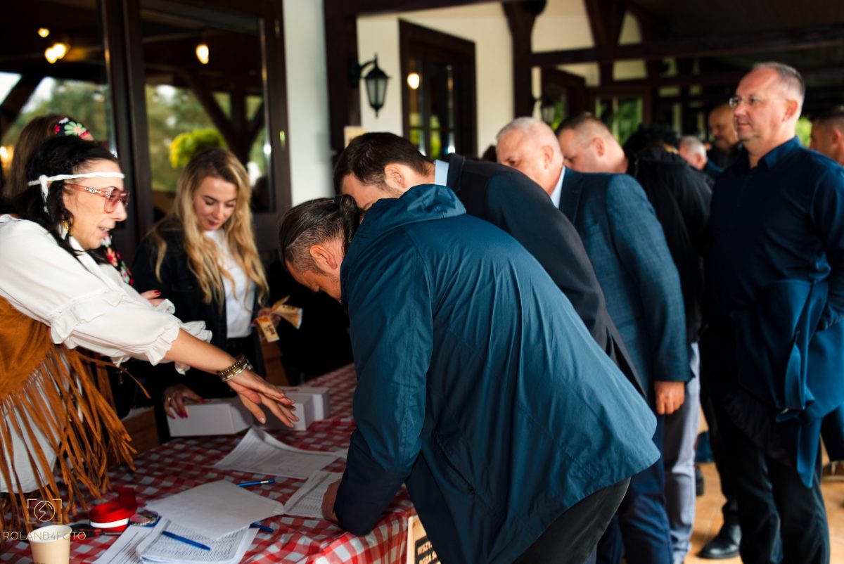 Rejestracja gości przy stole z obrusem w kratkę na wejściu na wydarzenie firmowe